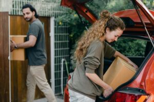 A couple taking boxes from their car and moving to a smaller space