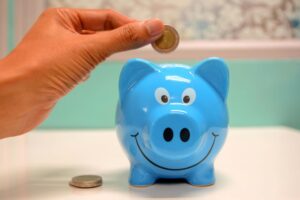 A woman putting a coin in her blue piggy bank