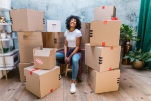 A woman sitting on a chair surrounded by boxes, ready to move, reflecting the need for practical moving tips for first-time renters