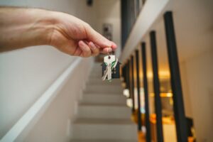 Person holding house keys inside a modern home, symbolizing safe renting and the need to spot rental scams before signing a lease