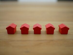 Small red figurines in the shape of a house, on a wooden surface.